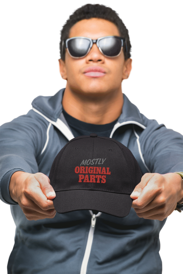 Man In sunglasses Holds out Mostly Original Parts Dad hat in Black with red /grey embroidery