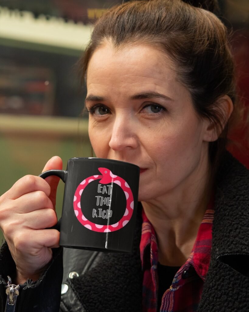 woman drinking from black mug with Pink and red Snake Eat The Rich slogan
